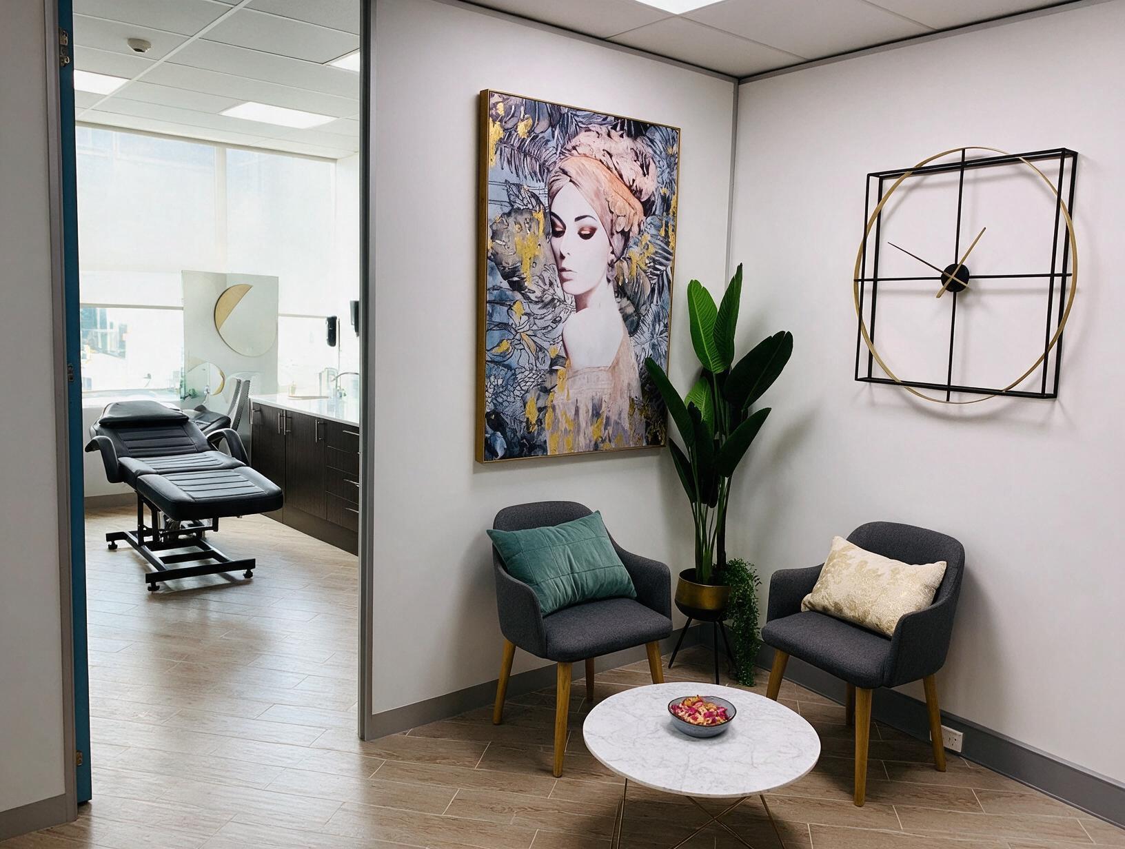 Reception nook with two grey armchairs, marble coffee table, large framed portrait and clock