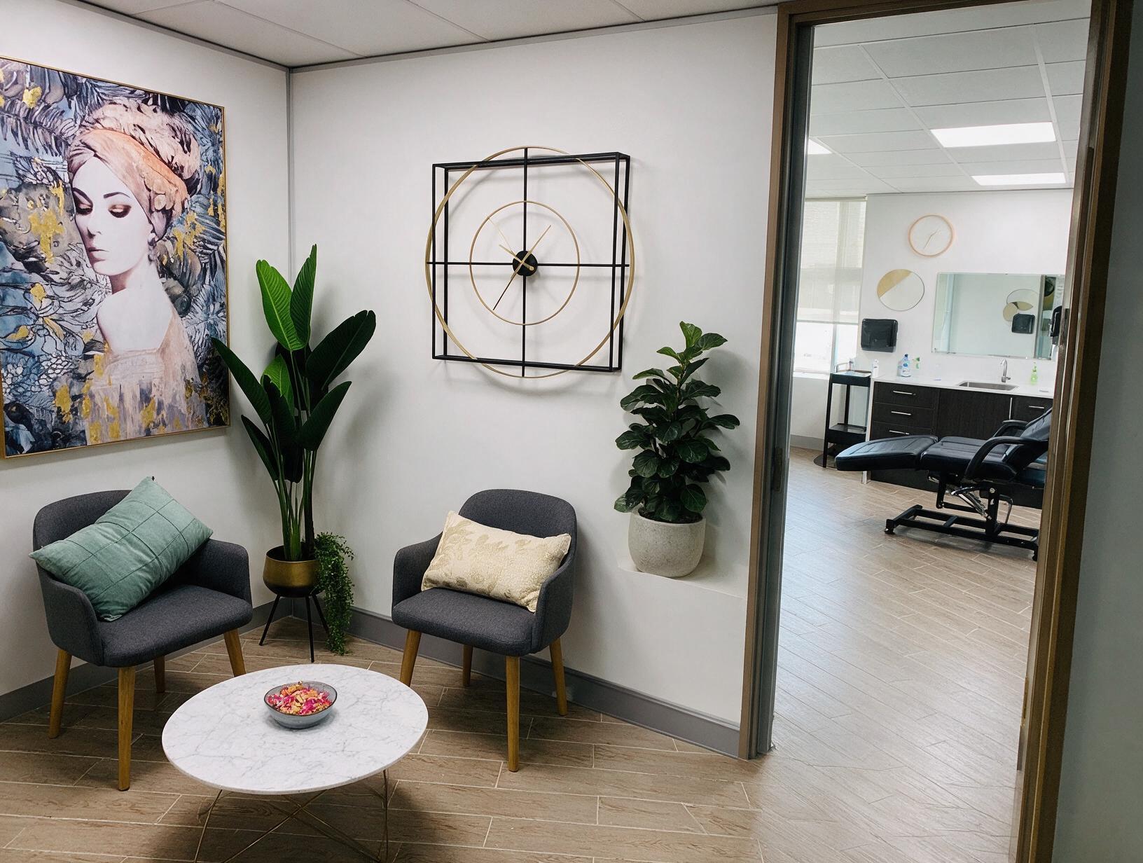Bright reception nook with two grey armchairs, a marble coffee table and plants
